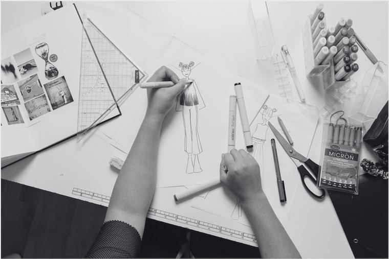 Hands sketching designs on paper