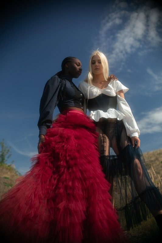 Two models in red and white tulle looks under a blue sky