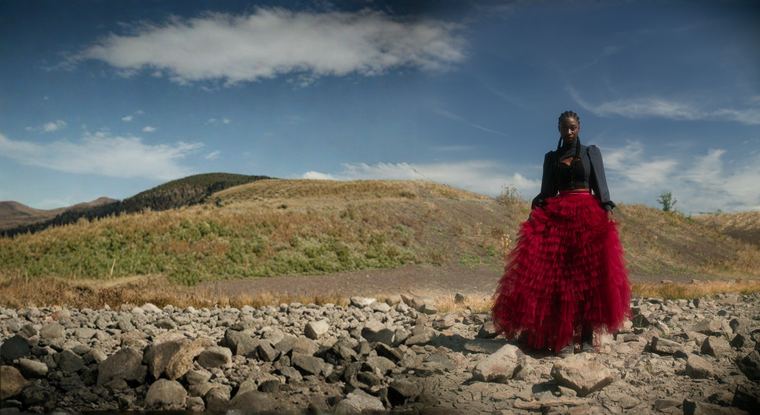 Model in a red tulle skirt standing in an open field