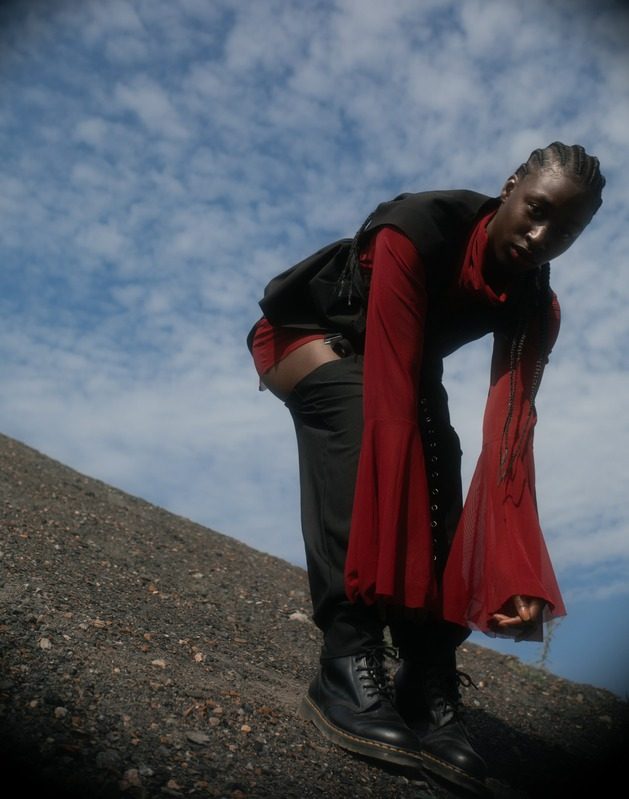 Model with long red bell sleeves bending forward