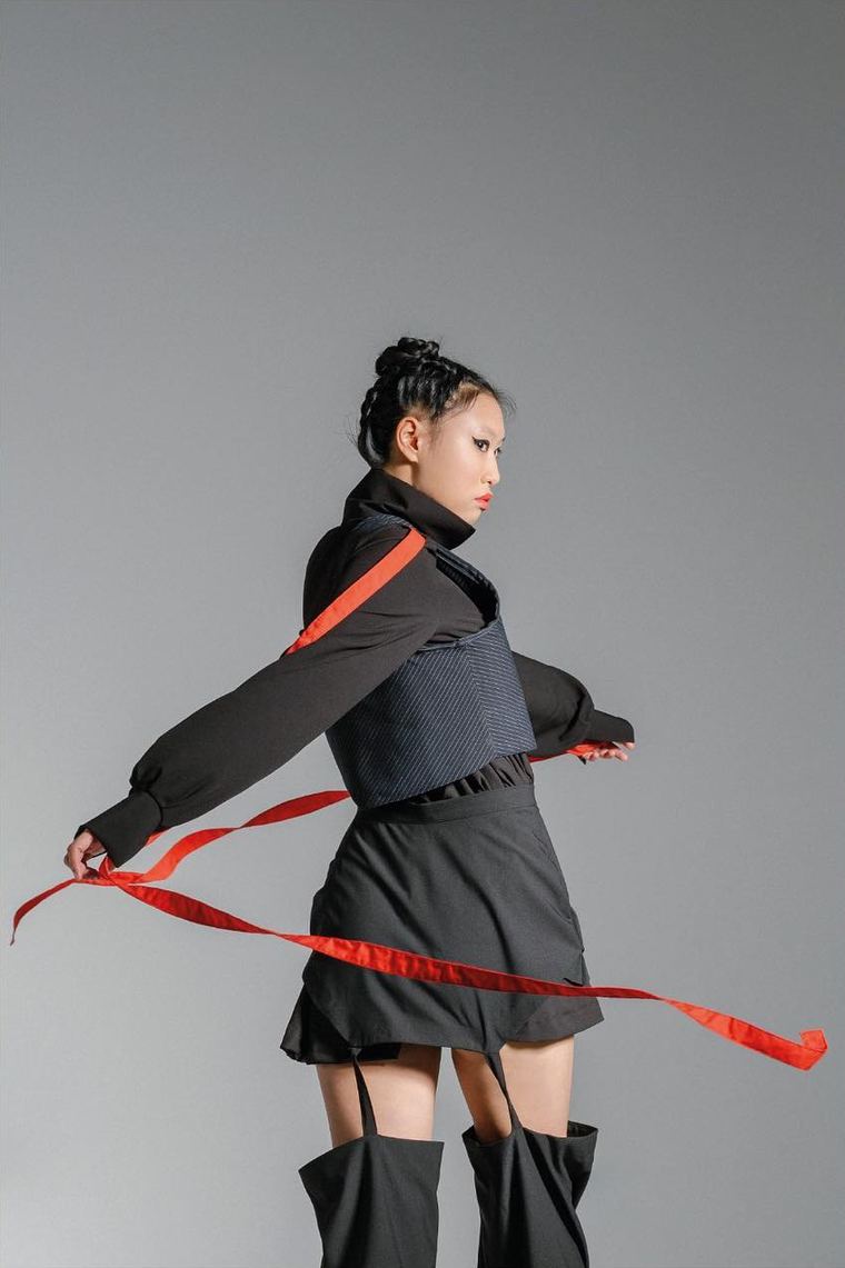 Red ribbon swirling around a black corset look