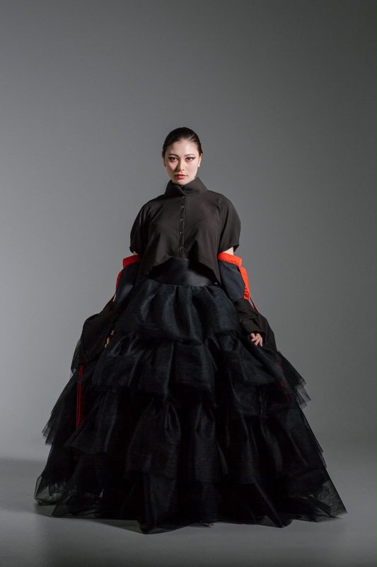 Full-length black tulle gown with red sleeve ties