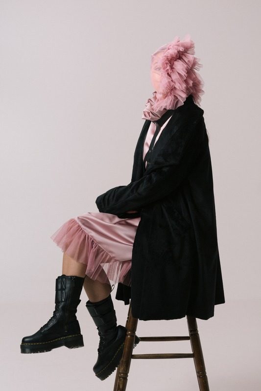 Seated on a stool in pink and black