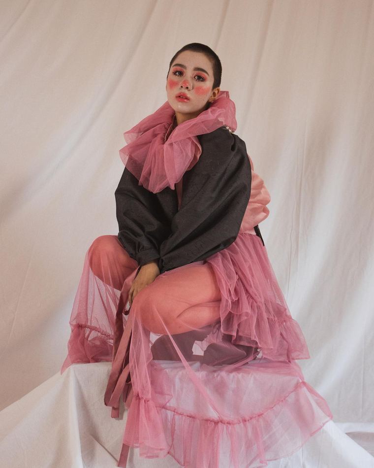Pink ruffle collar with black jacket, seated