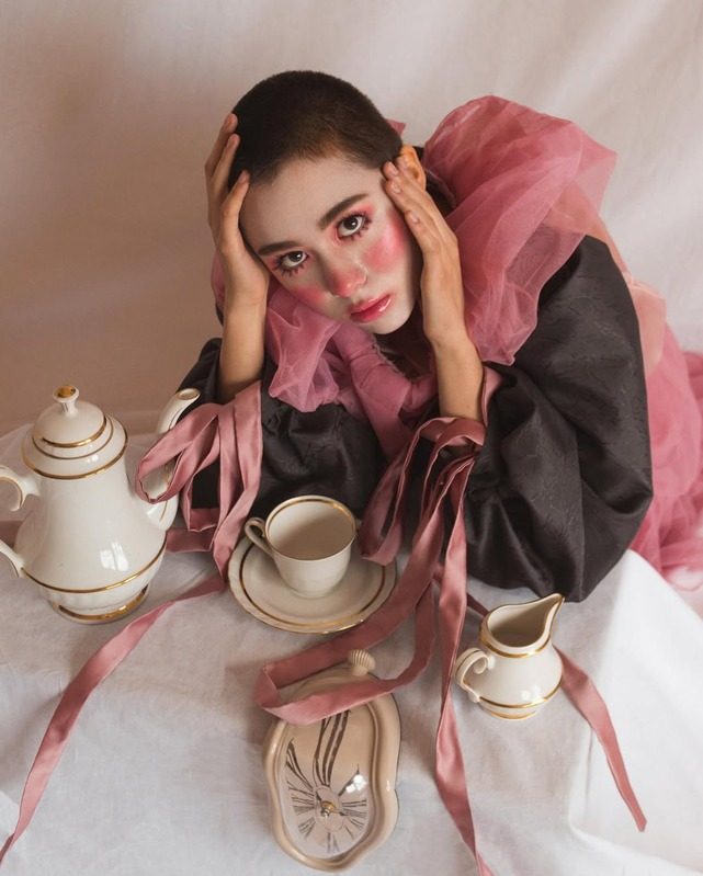 Model with a pink ruffle collar between teacups